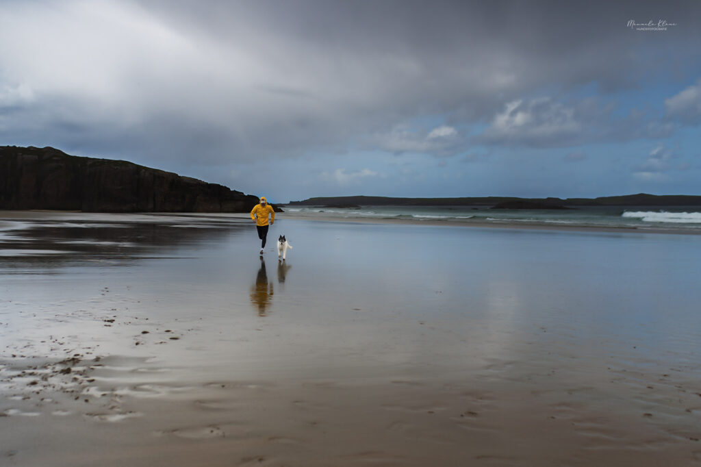 Wettrennen zwischen Mann und Hund am Strand in Schottland